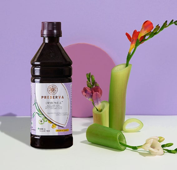 Diabewell Juice next to bamboo shoots with red, maroon and white colour flowers on a purple background.