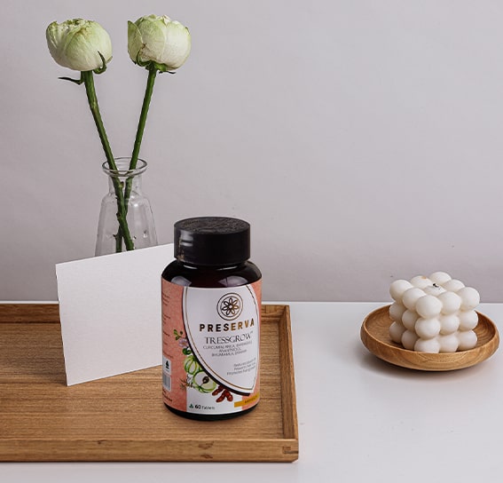 Tressgrow Tablets on a wooden tray with a glass flower vase next to a round wooden tray with the designed candle.