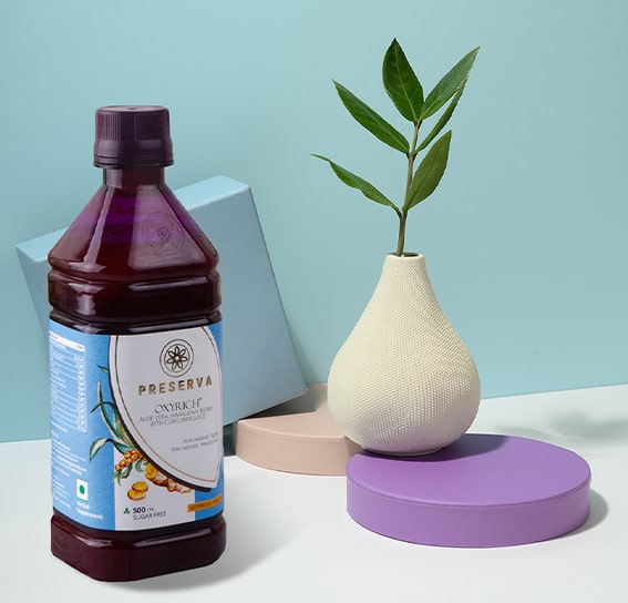 Oxyrich Juice next to a designer flower pot on two circle-shaped stands and a box behind it.