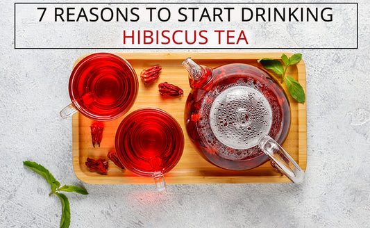 Hibiscus Tea in a glass pot and two cups on a wooden tray with mint leaves