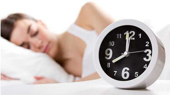 Small black and white alarm clock with a woman sleeping behind