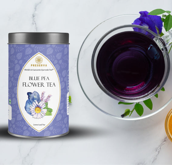Preserva Wellness Blue Pea Tea 50 grams box next to a glass cup filled with the dark blue colour Blue Pea Tea in the cup and a Shankhpushpi flower.