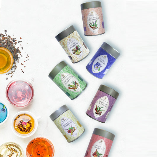 Seven Preserva Wellness small tea containers next to various coloured teas in cup