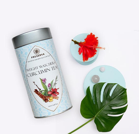 Weight Watcher Curcumin Tea next to a hibiscus flower and pearls & a leaf on two round-shaped stands.