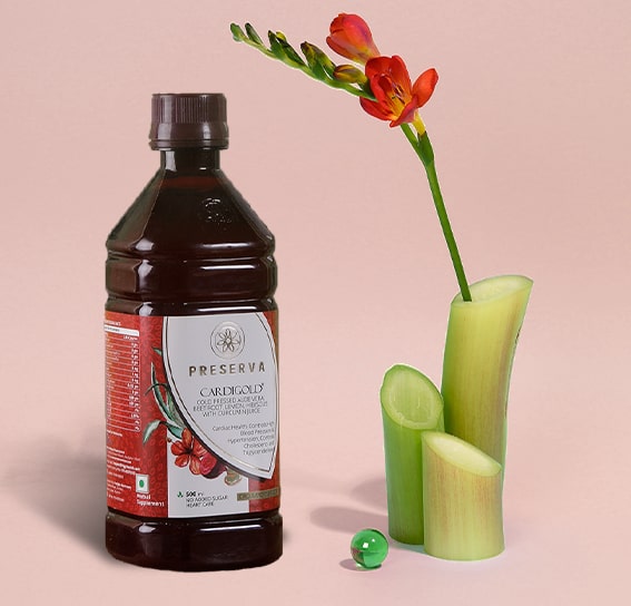 Cardigold Juice next to bamboo shoots, a flower and a marble ball with a light red background.